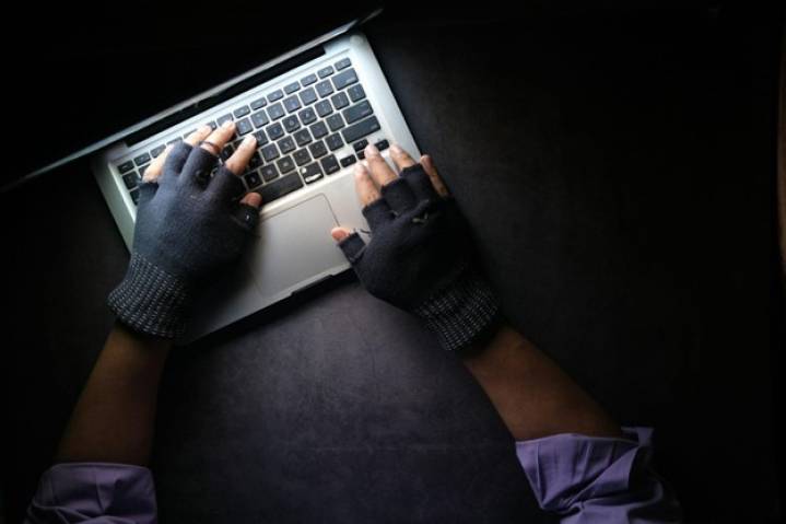 Image showing a man with gloves trying to steal data from a computer