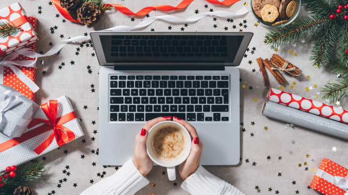 lady holding a warm cup of coffee next to her laptop for holiday season greetings 2024