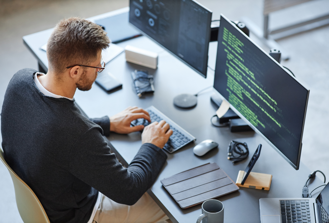 A cybersecurity expert working at a desk with multiple monitors displaying code and security protocols, focusing on data protection and digital security measures.