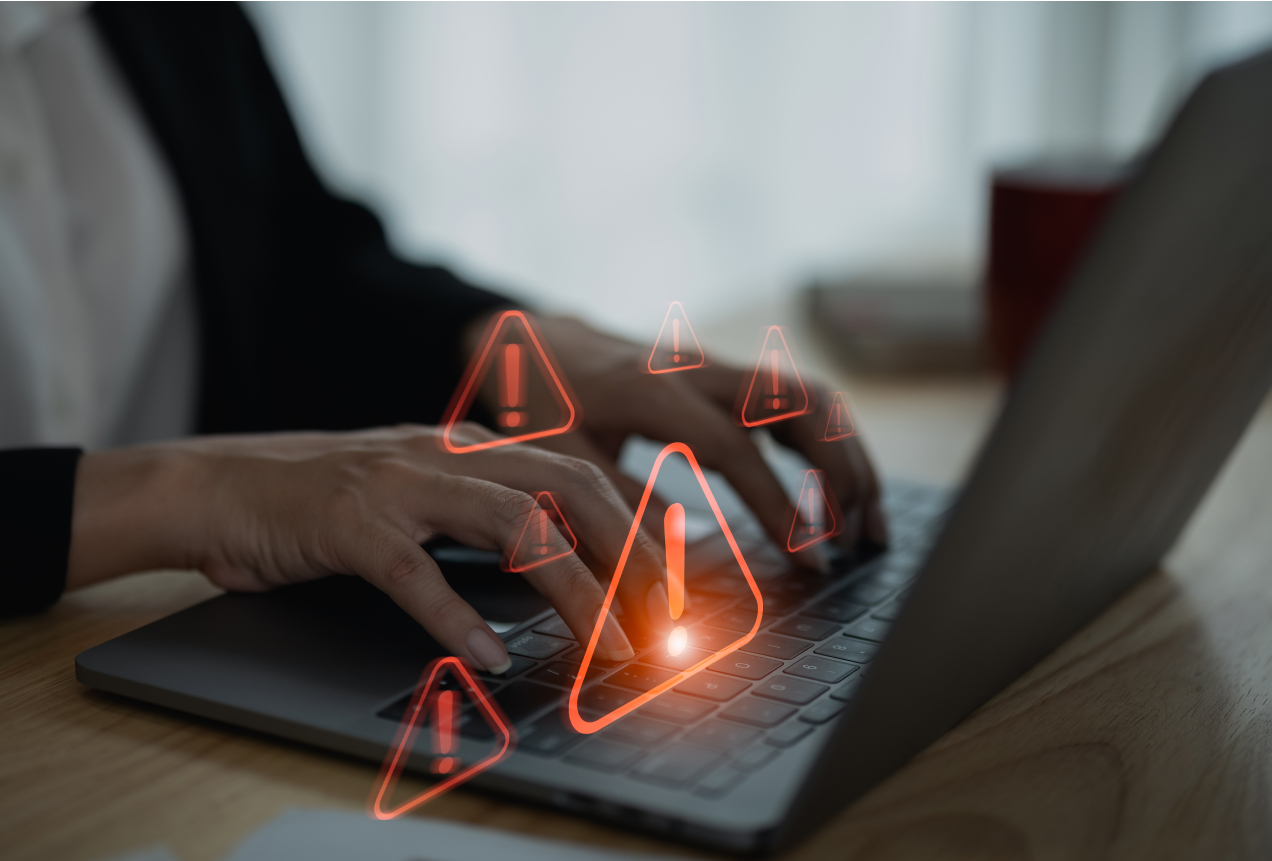 A person typing on a laptop with multiple red warning icons floating above the keyboard, symbolizing the importance of securely wiping files using BCWipe for data protection.