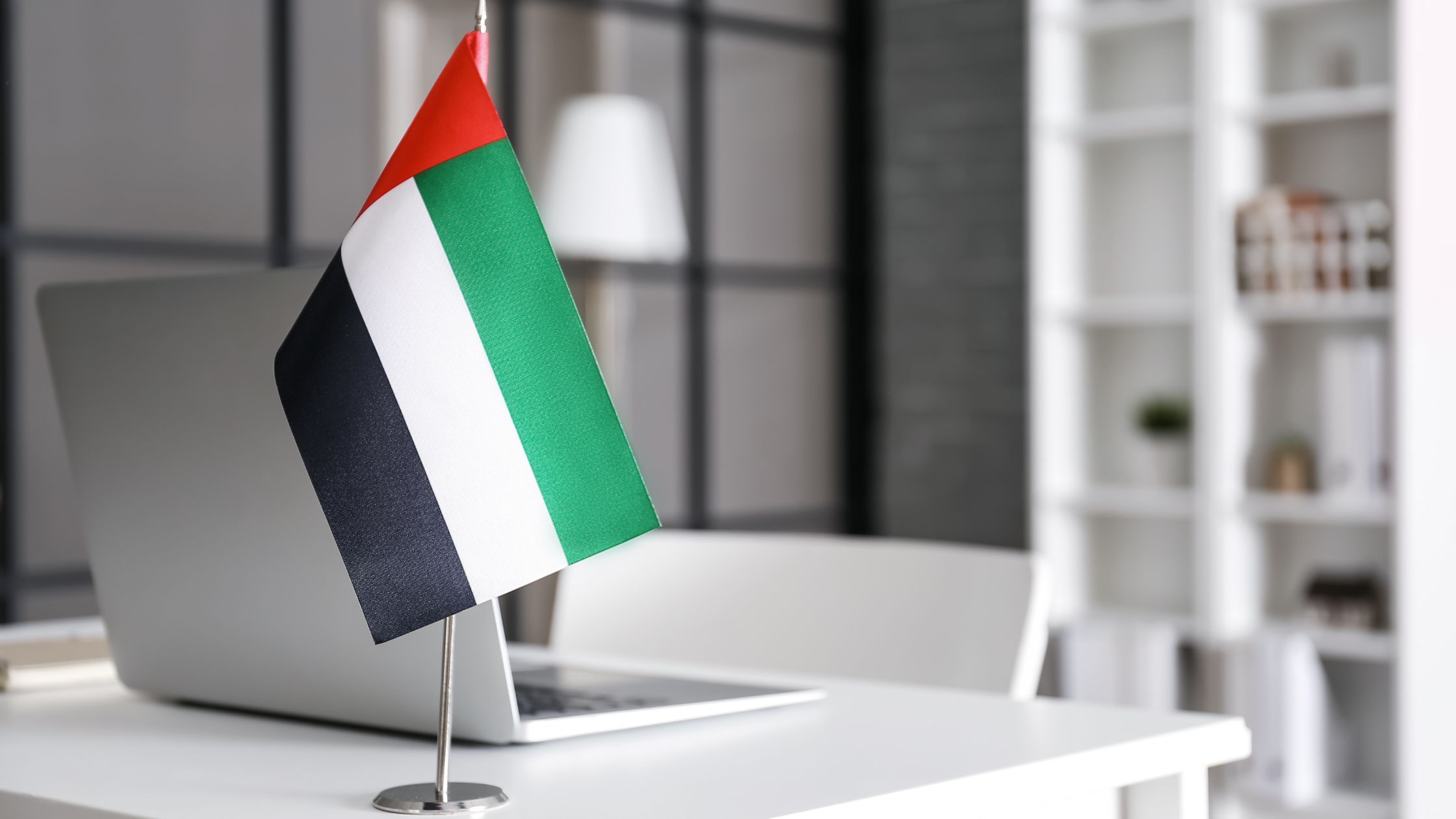 Office desk with a laptop and UAE flag, representing compliance with NESA cybersecurity standards in the United Arab Emirates.