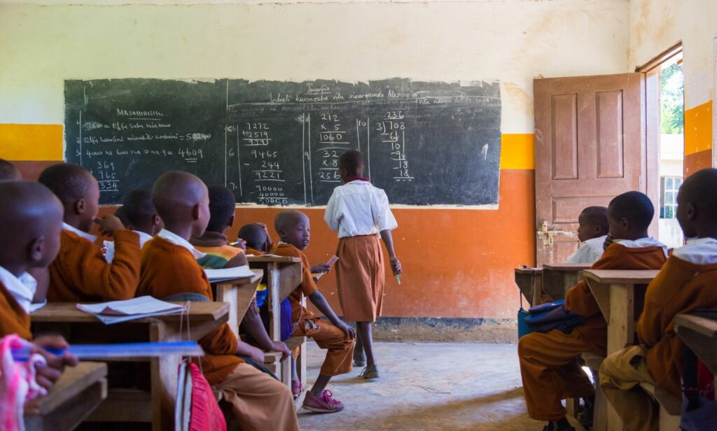 Kid writing on a blackboard school in an underprivileged community for a non-profit initiative