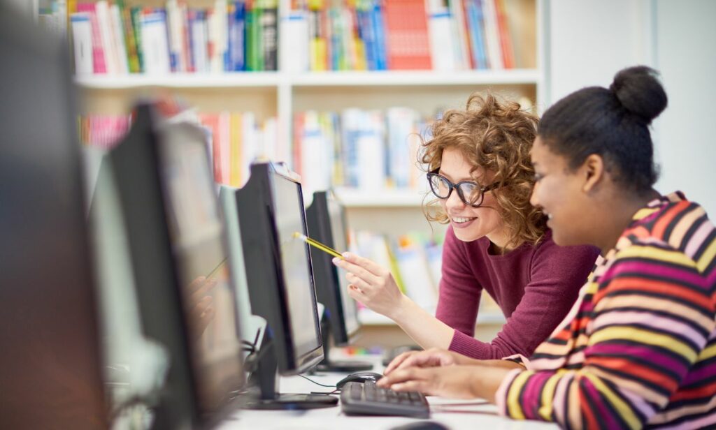 Teacher with student using a computer sanitized with BCWipe Total WipeOut